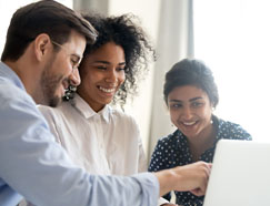 Three diverse workers huddled around computer