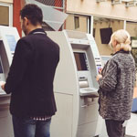 Man at ATM.  Close by a woman is at an ATM.  